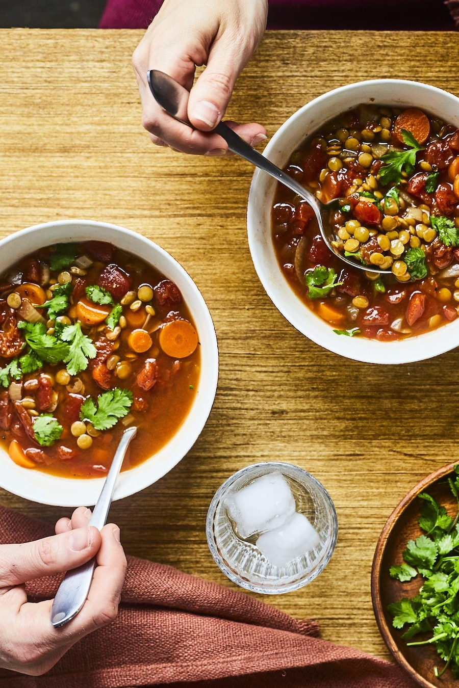Deux bols de soupe aux lentilles à la marocaine à la mijoteuse sur une table en bois.