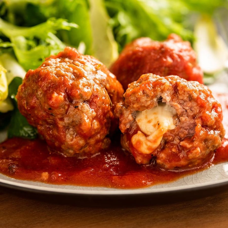 Des boulettes de viande et fromage accompagnées d'une salade dans une assiette.