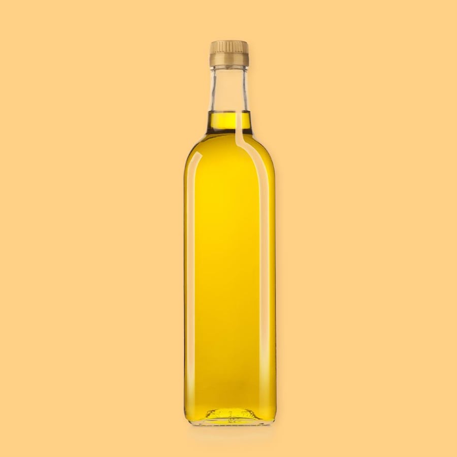 Une bouteille d'huile canola sur un fond jaune.