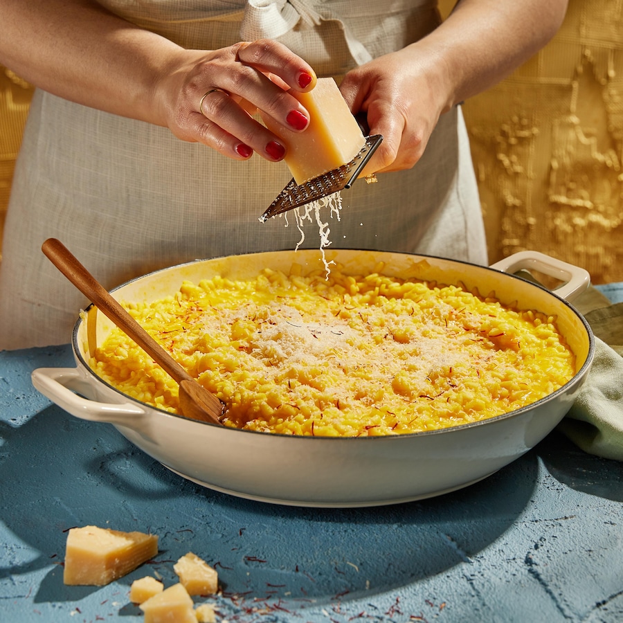 Un plat de risotto sur lequel on ajoute du fromage râpé.