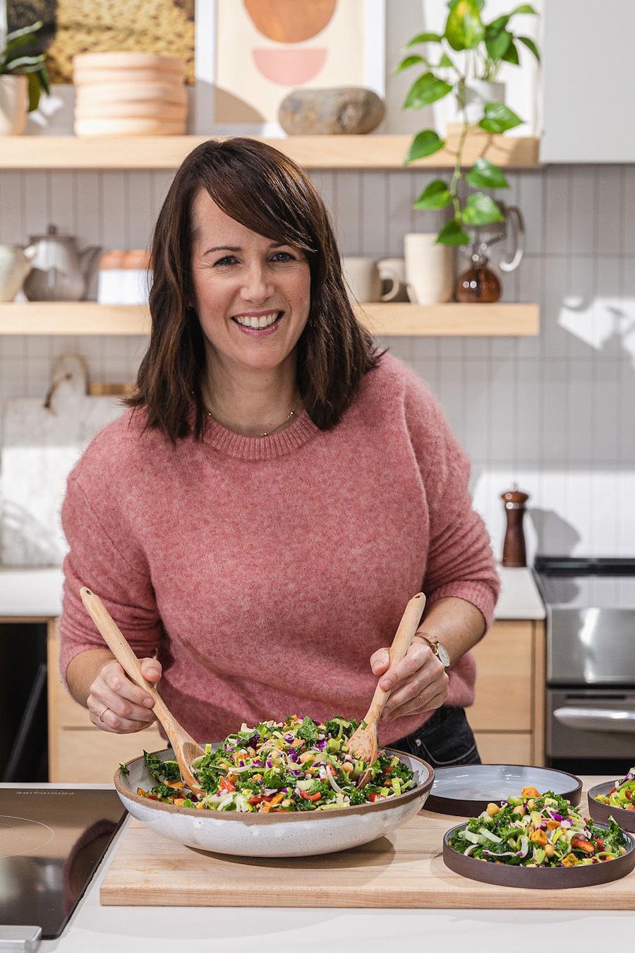 La nutritionniste Genviève O'Gleman se tient debout dans une cuisine et portionne une salade dans trois assiettes.