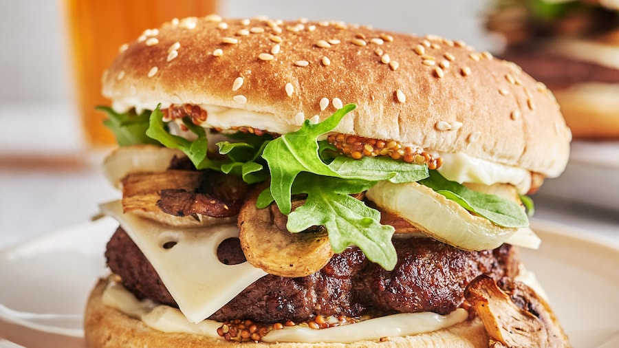 Un burger garni aux champignons dans une assiette.