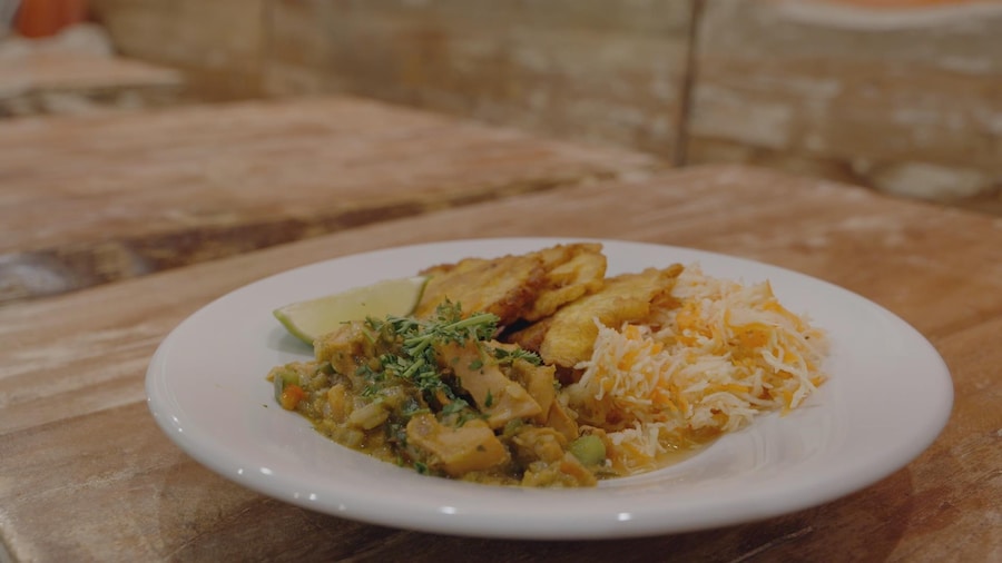 Une assiette ronde contient du lambi, du riz et un quartier de lime. Le plat est posé sur une table du restaurant. 