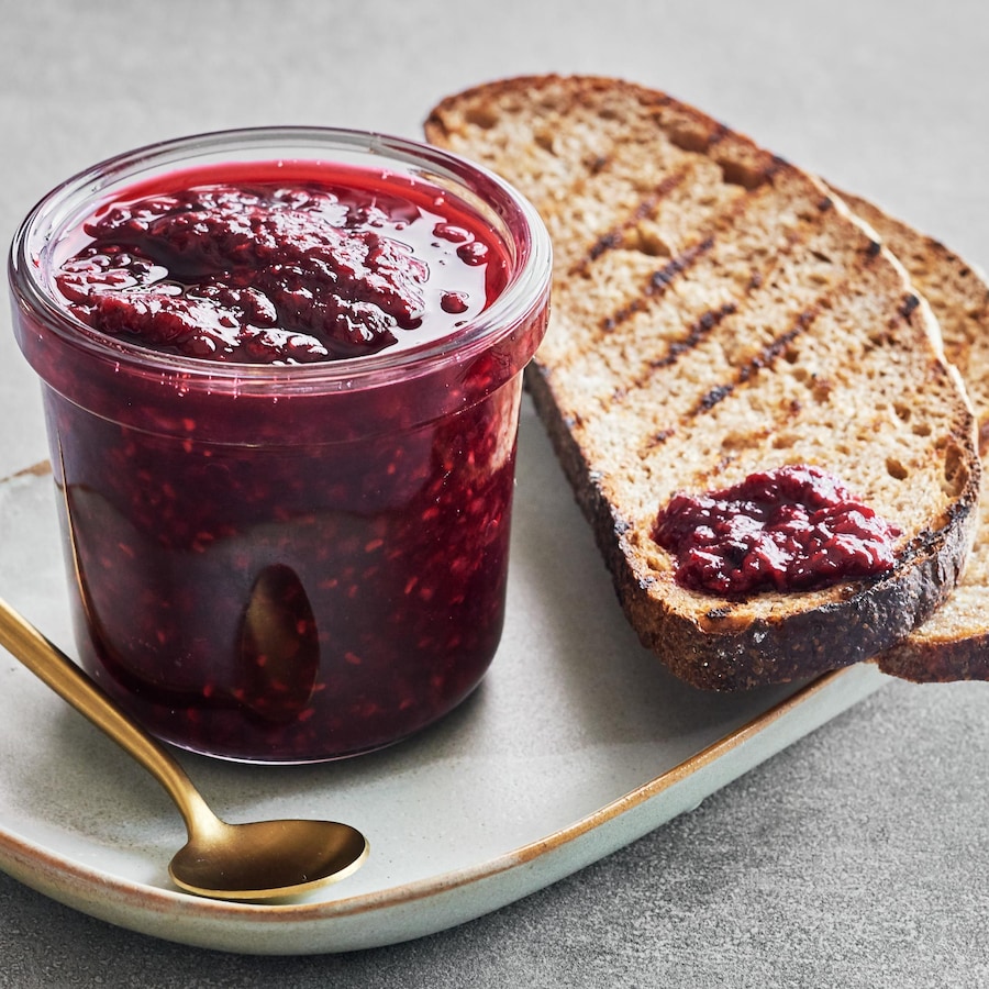 Un pot de confiture avec deux tranches de pain grillé.