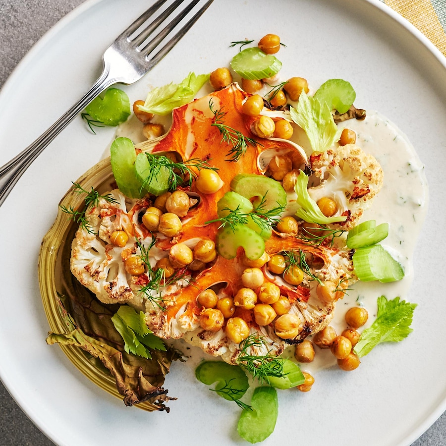 Un « steak » de chou-fleur épicé avec une sauce ranch au tahini dans une assiette.