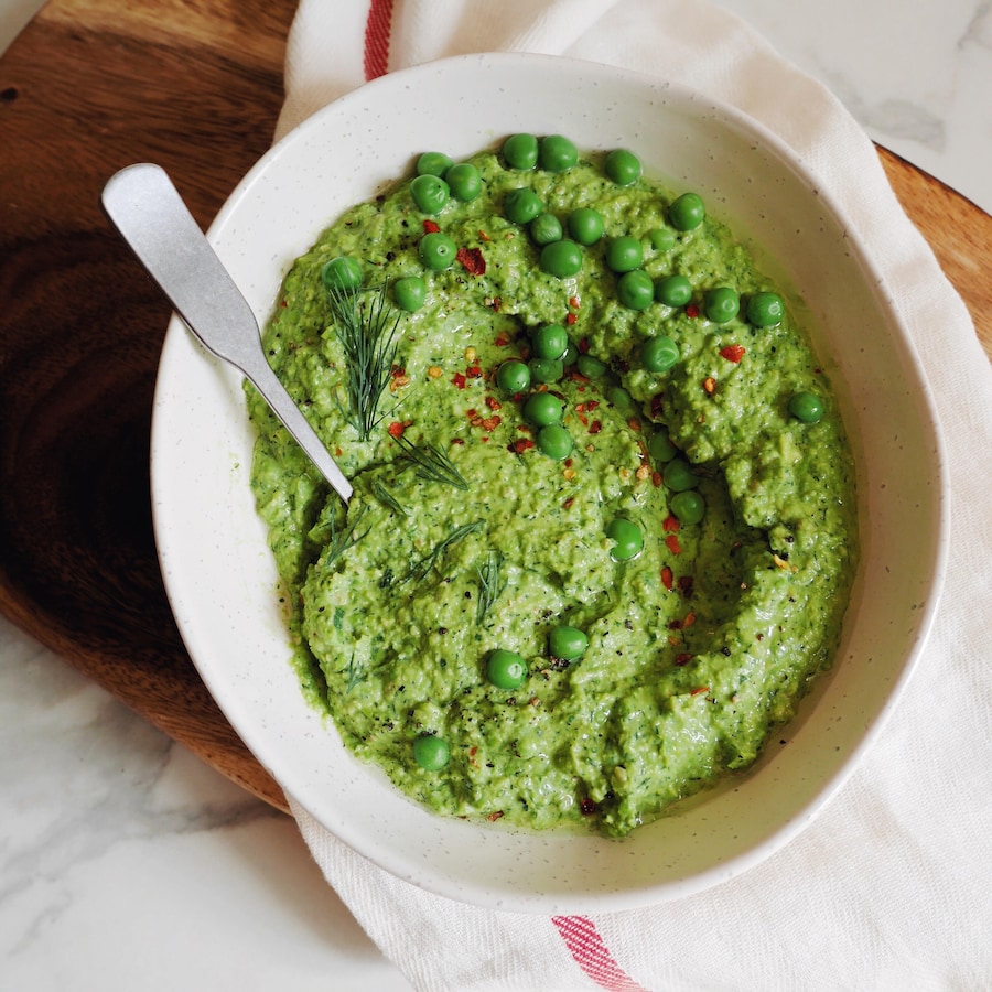 Un plat de pesto de petits pois aux herbes avec une cuillère.