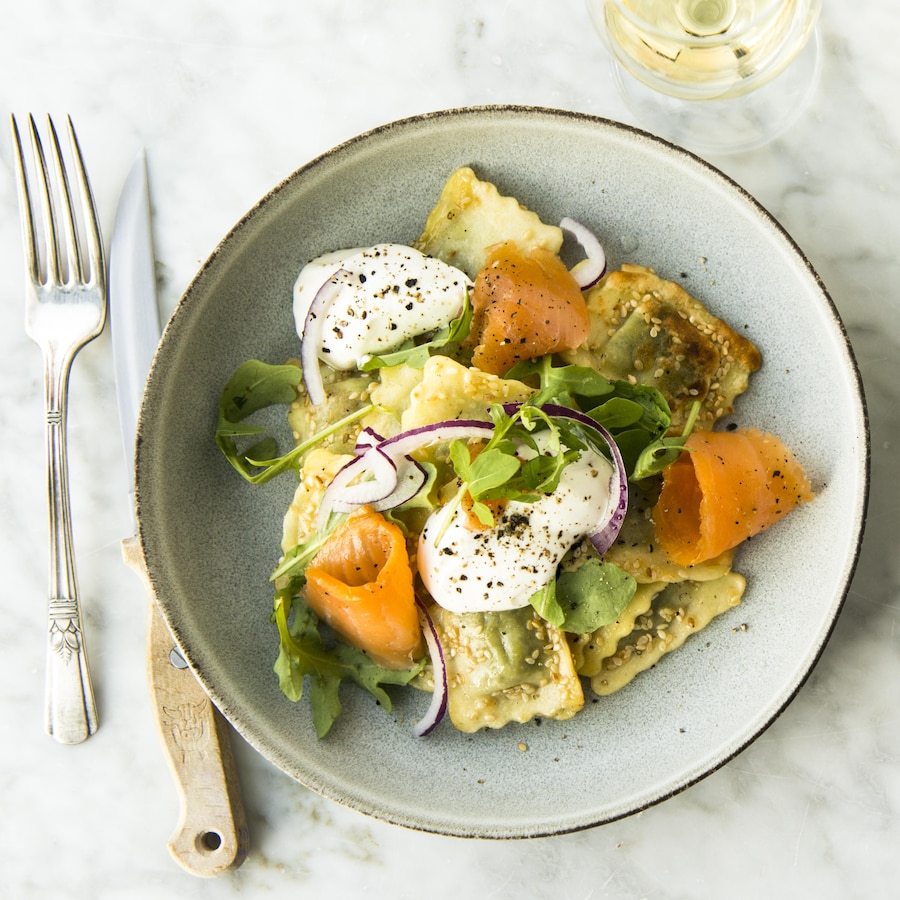 Deux assiettes de raviolis au fromage et saumon fumé garnis de roquette vues de haut.