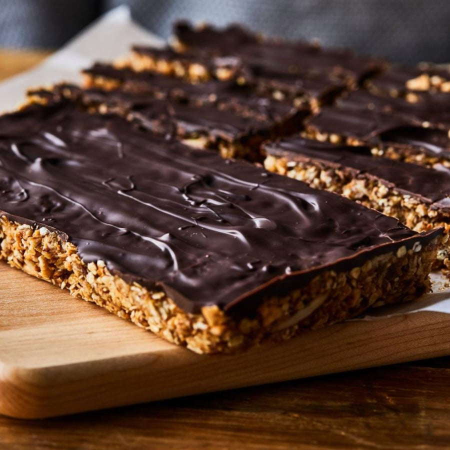 Des barres tendres nappées de chocolat sur une planche de bois.