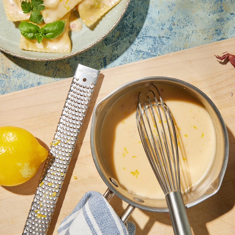 Une casserole de beurre blanc au citron près d'un plat de raviolis.
