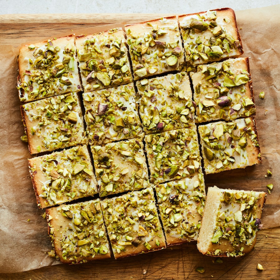 Des blondies aux pistaches et à l'eau de fleur d'oranger coupés sur un papier parchemin. 