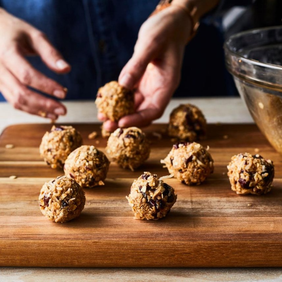 Des boules coco-canneberges sur une planche en bois.