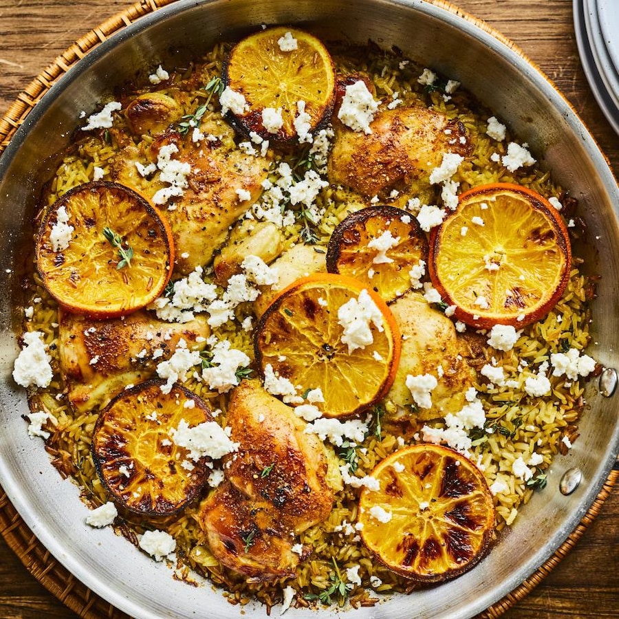 Un grand poêlon garni de poulet à l’orange et de fromage feta disposé sur une table.