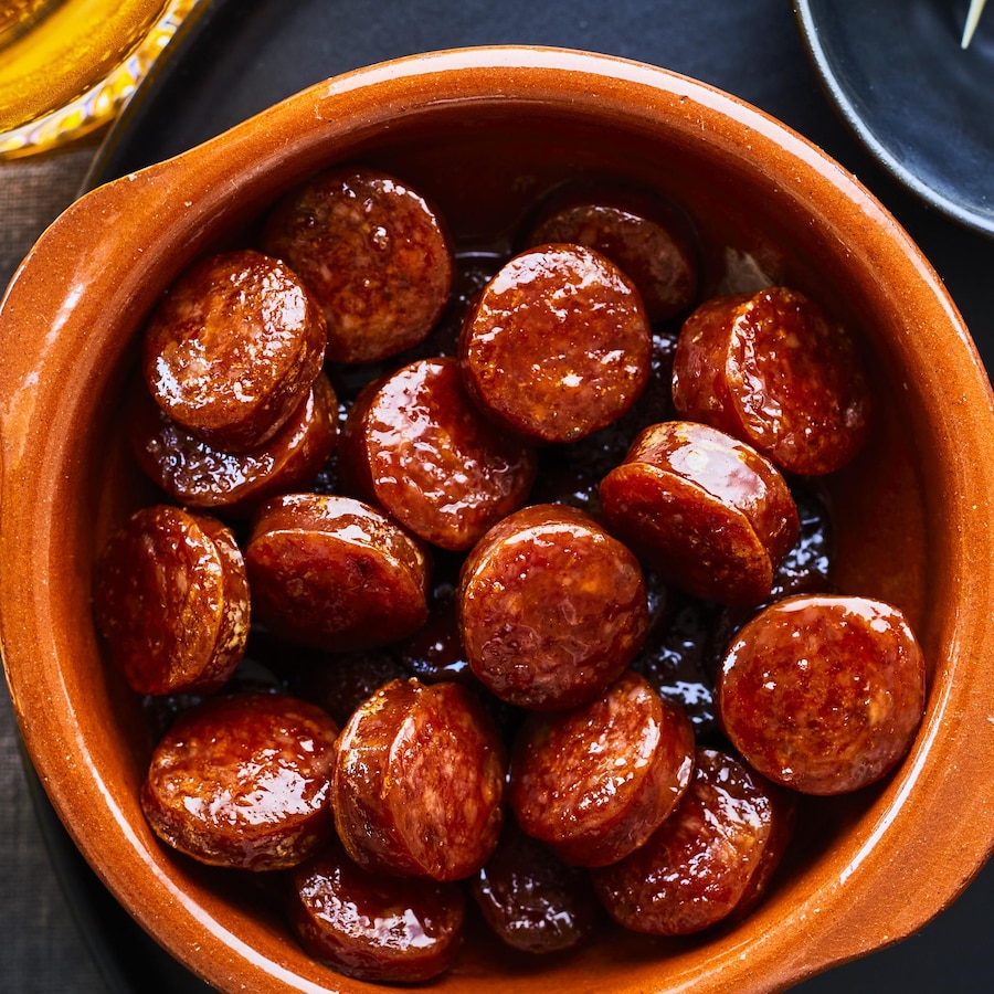 Bol rempli de tranches de chorizo caramélisées à l'érable et servi avec des olives.