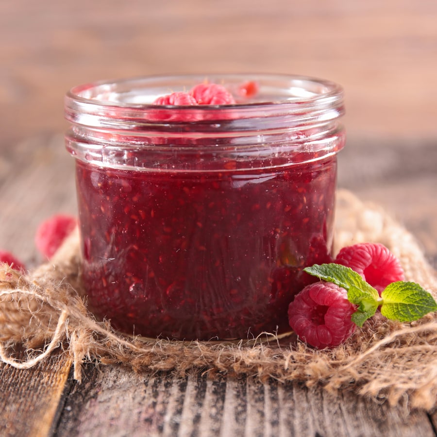 Un pot Mason rempli de confiture de framboises.