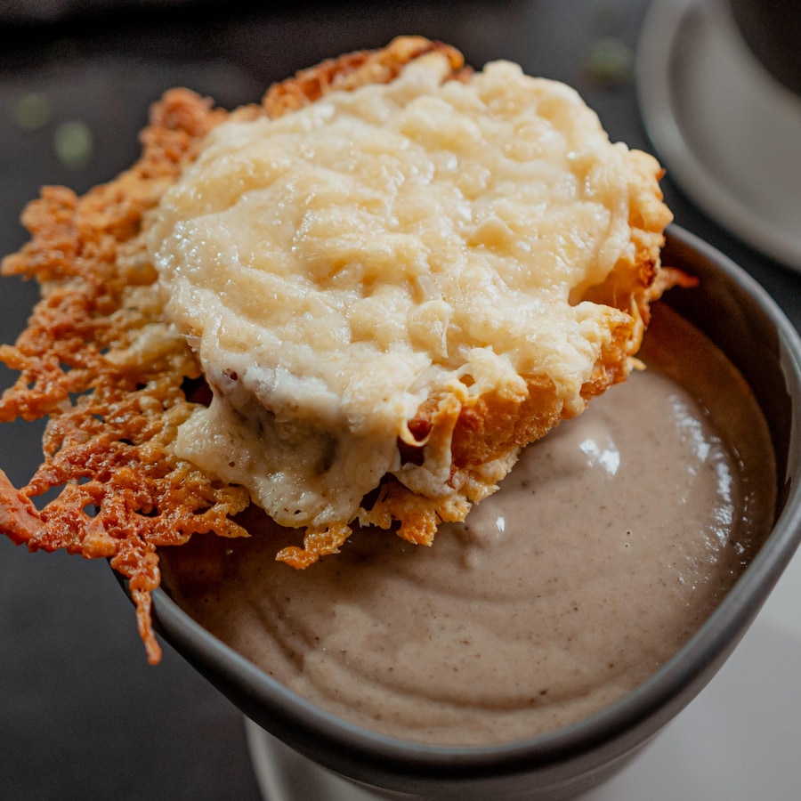 Une crème de champignons dans un bol avec un croûtons de fromage sur le dessus.