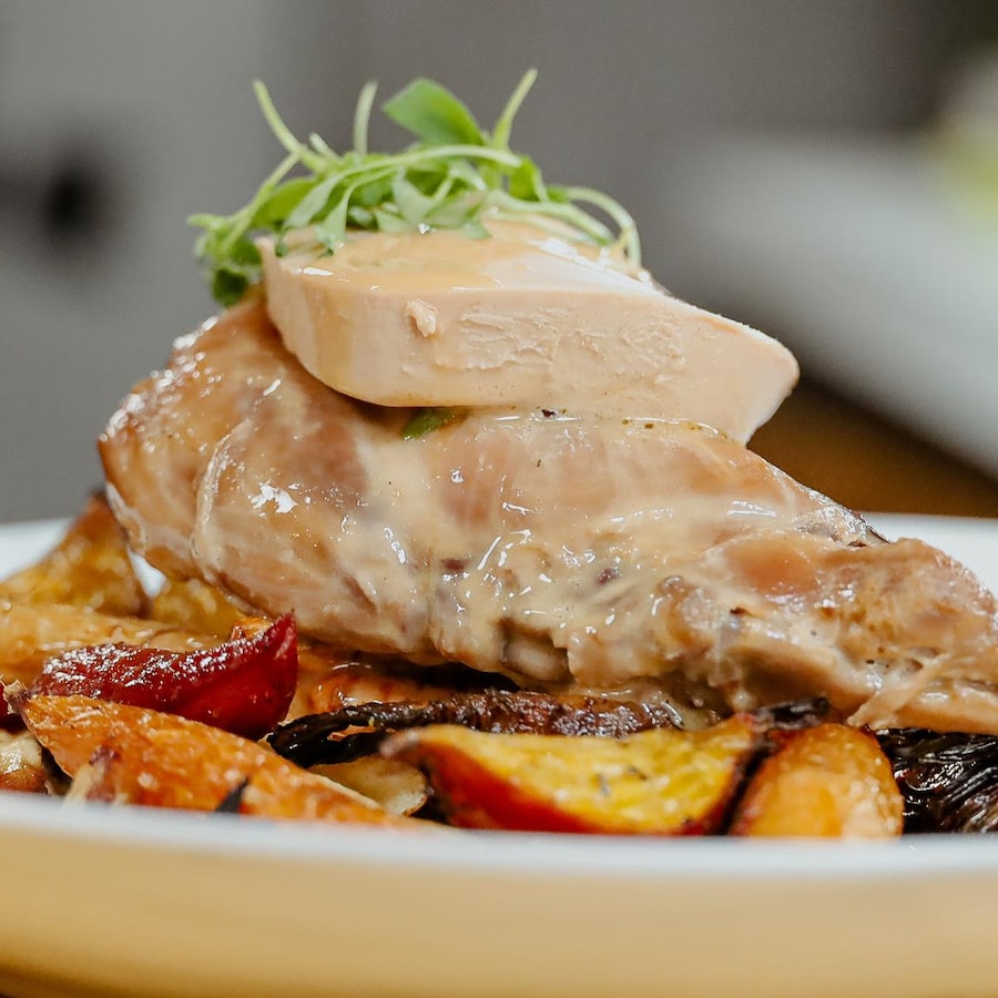 Cuisse de lapin braisée servie sur des pommes de terre et garnie d'une tranche de foie gras.