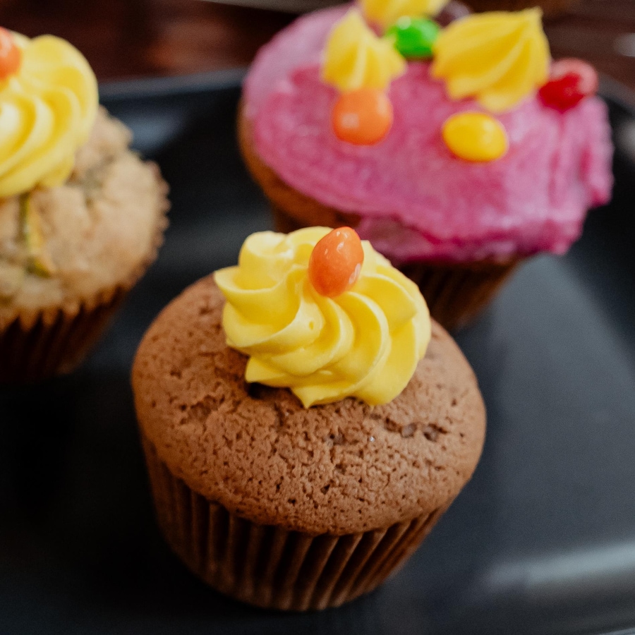 Des cupcakes garnis de glaçage de différentes couleurs et de bonbons.