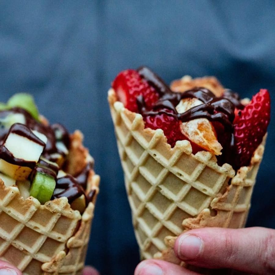 Deux cônes avec des fruits et de la fondue au chocolat.