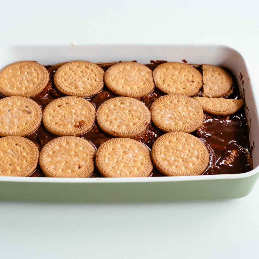 Des biscuits et de la crème anglaise au chocolat disposés en couche successives dans un moule à gâteau.