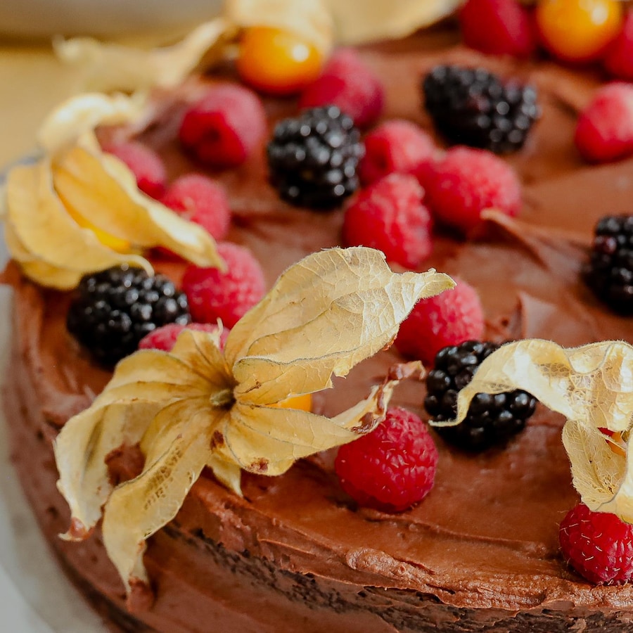 Un gâteau au chocolat garni de mûres, de framboises et de cerises de terre.