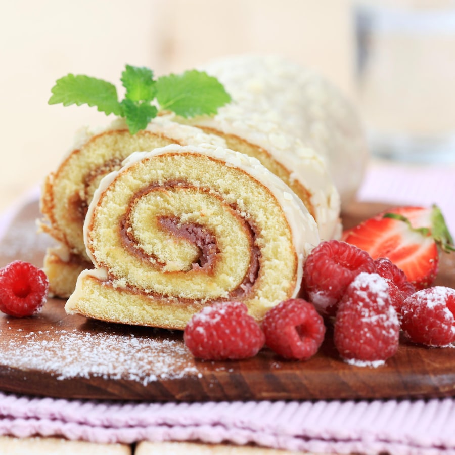 Un gâteau roulé à la confiture avec quelques framboises et fraises.