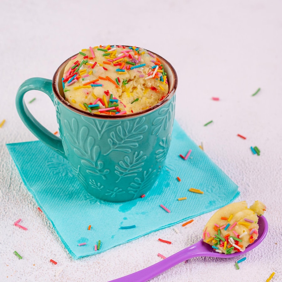 Un gâteau à la vanille dans une tasse avec des confettis sur le dessus.