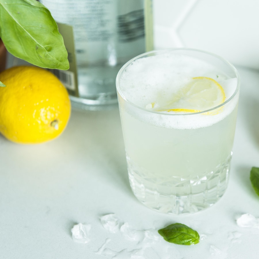 Une personne verse un gin citron-basilic sour dans un verre.