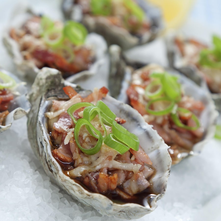 Six huîtres bien garnies prêtes à être dégustées.