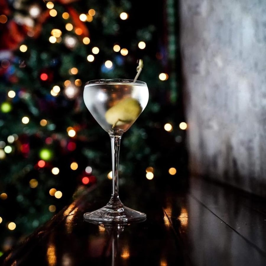 Un verre de martini bien rempli devant un sapin de Noël.