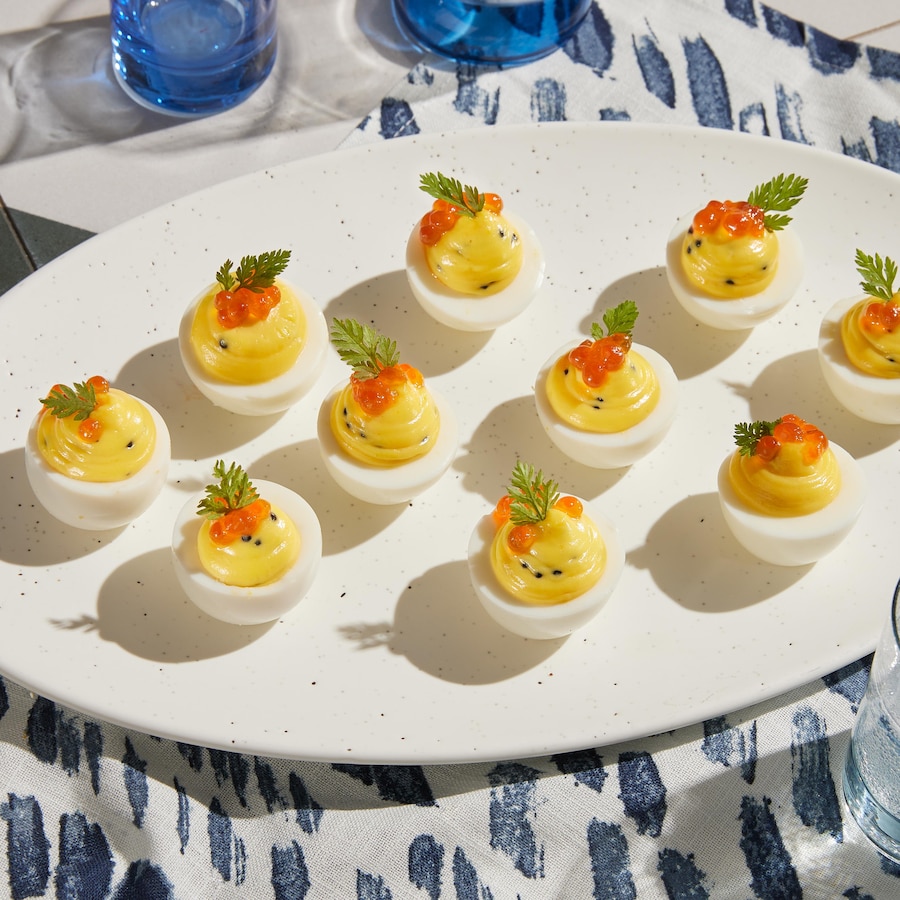 Des œufs mimosa avec du caviar en garnitures sont disposés dans une assiette de présentation.
