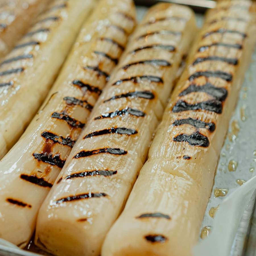 Des poireaux confits grillés sur une plaque à cuisson.