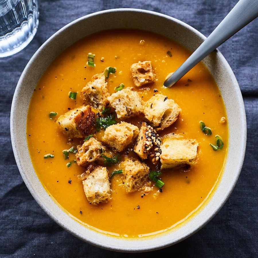 Bol de potage orangé à la courge musquée avec croûtons de pain. 