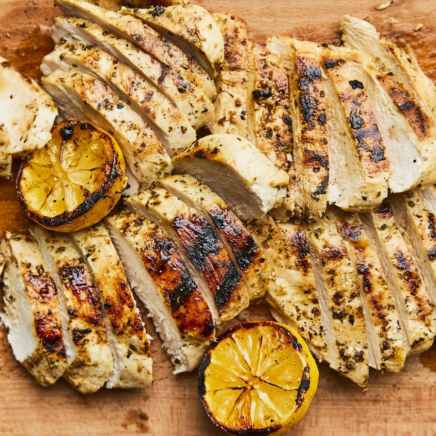 Poulet au citron grillé étalé sur une planche en bois.