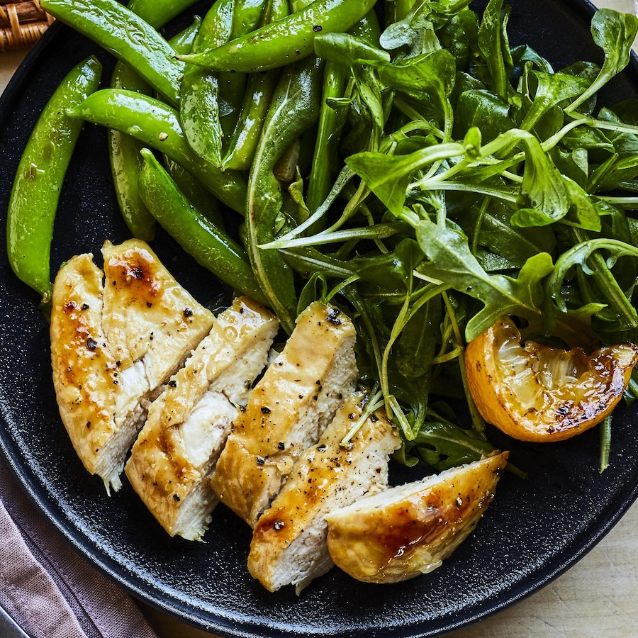 Assiette de poulet au miel et au citron avec tomates et roquette.
