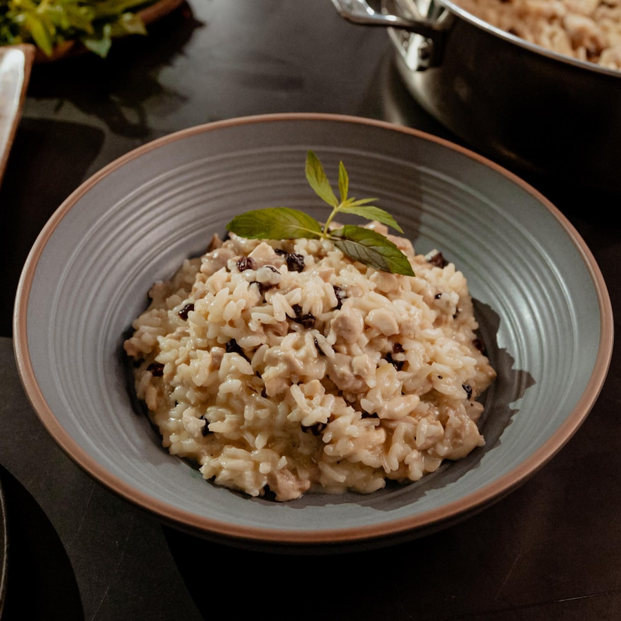 Un bol de risotto au poulet et aux raisins secs garni de menthe fraîche.