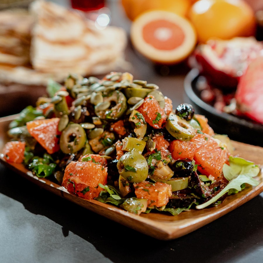 Une salade fraîche aux oranges, à la roquette et aux olives dans une assiette.