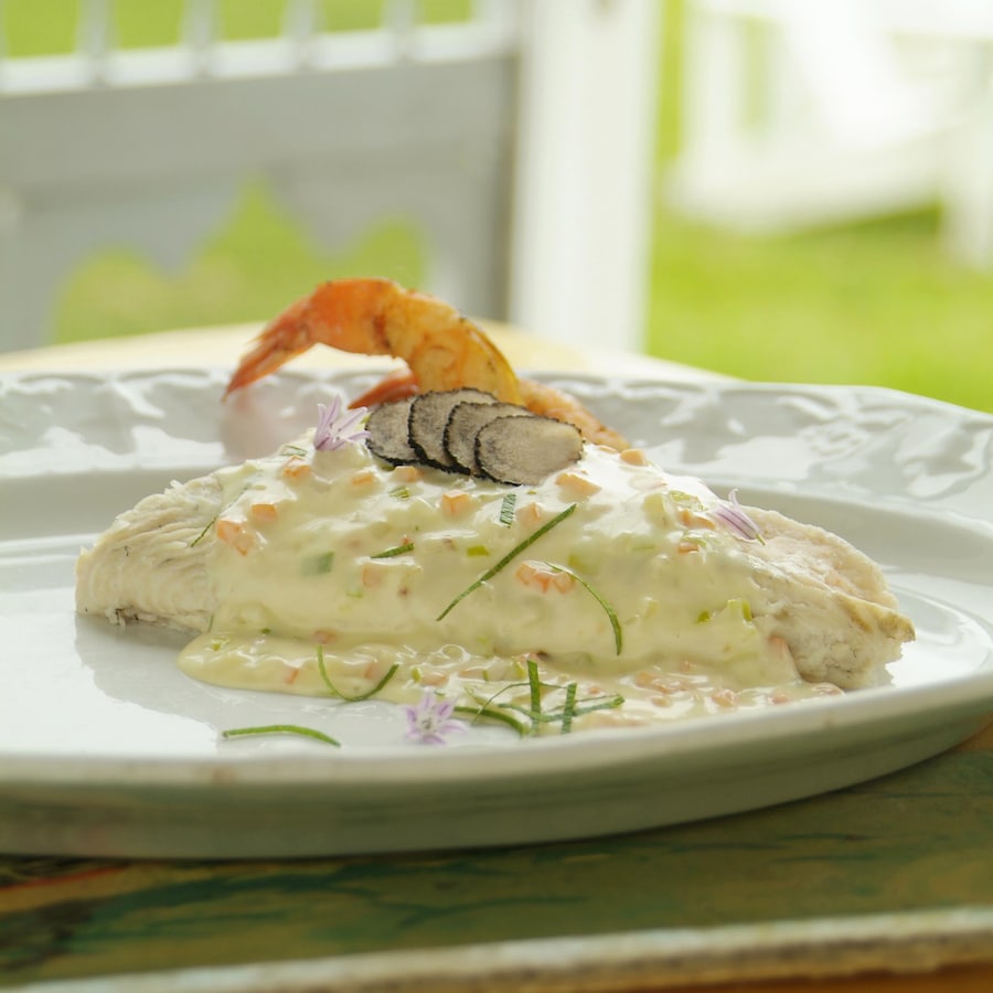 Soles farcies à la mousseline de crevettes, fumet court crémé dans une assiette.