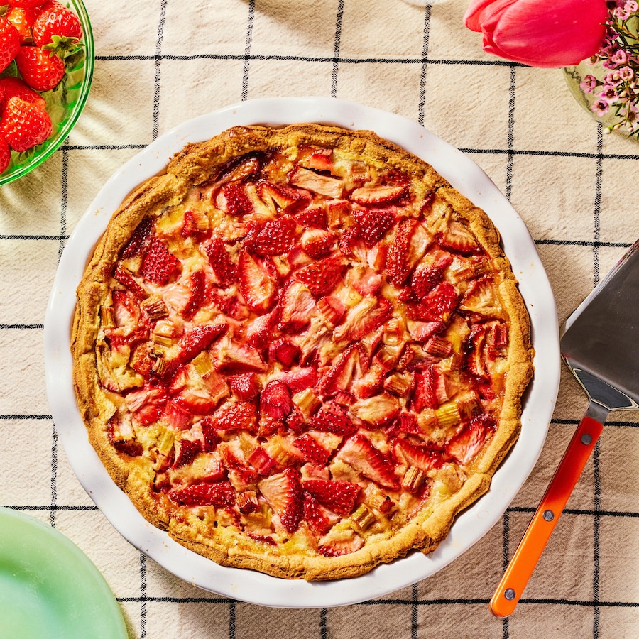 Une tarte fraises et rhubarbe à la crème pâtissière posée sur une table.