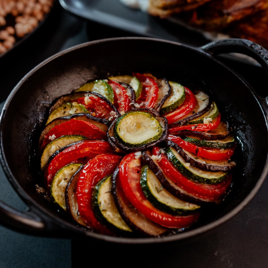 Des rondelles de légumes grillées superposées dans une casserole en fonte ronde. 