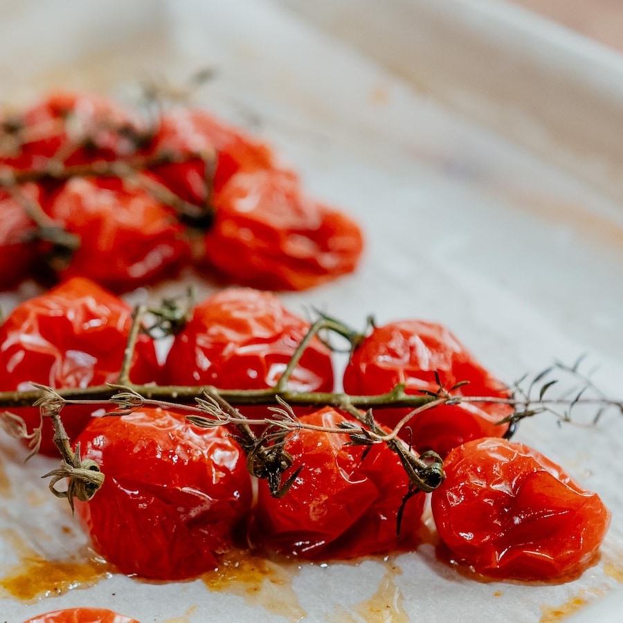 Des grappes de tomates cerises rôties sur une plaque à pâtisserie.