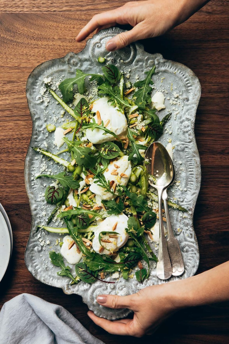 Une assiette de service avec une salade d'asperges aux amandes grillées avec des œufs pochés.