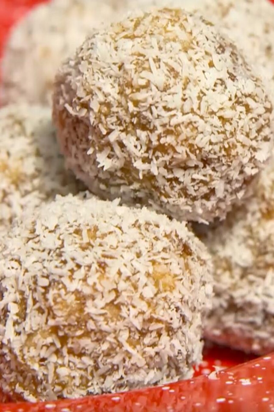 Des boules saupoudrées de noix de coco dans une assiette rouge.