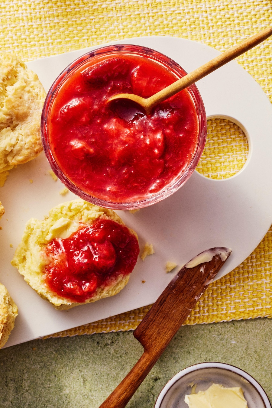 De la confiture fraises et rhubarbe servie avec des scones et du beurre.