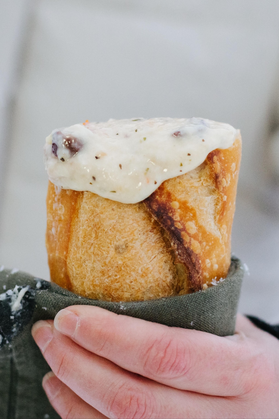 Une main tient une fondue au fromage dans une baguette.