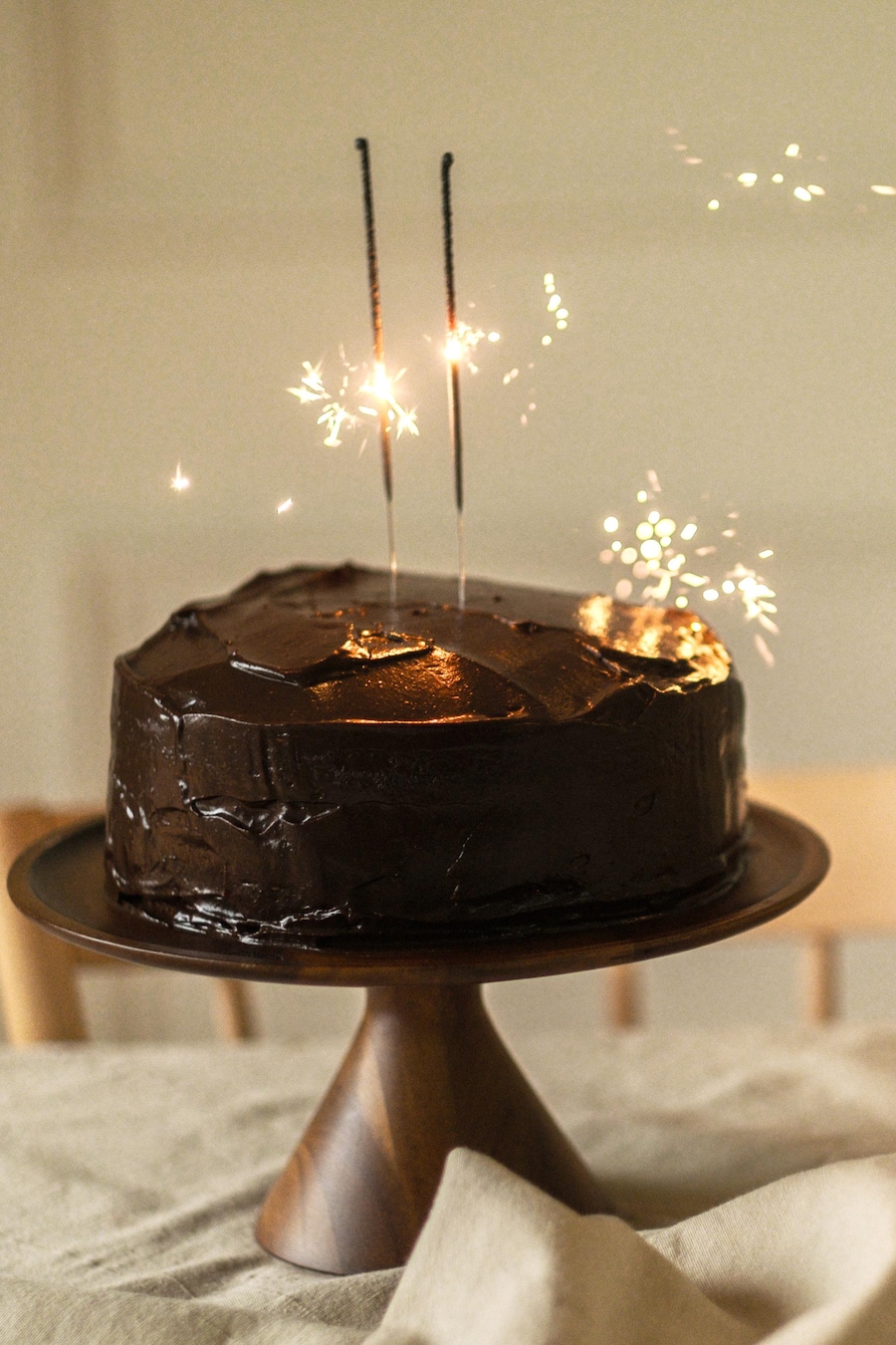 Un gâteau au chocolat sur un porte-gâteau, avec des chandelles allumées.