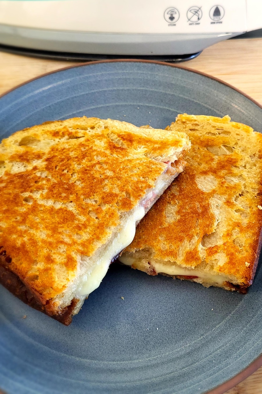 Un grilled cheese prêt à être dégusté dans une assiette bleue.