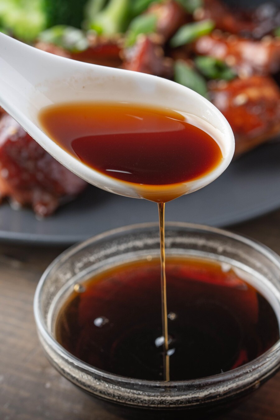 Une cuillérée de sauce teriyaki au-dessus du bol rempli de sauce. 