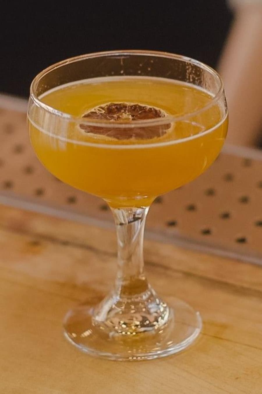 Un verre rempli d'un mocktail orangé avec une rondelle de citron déshydratée.