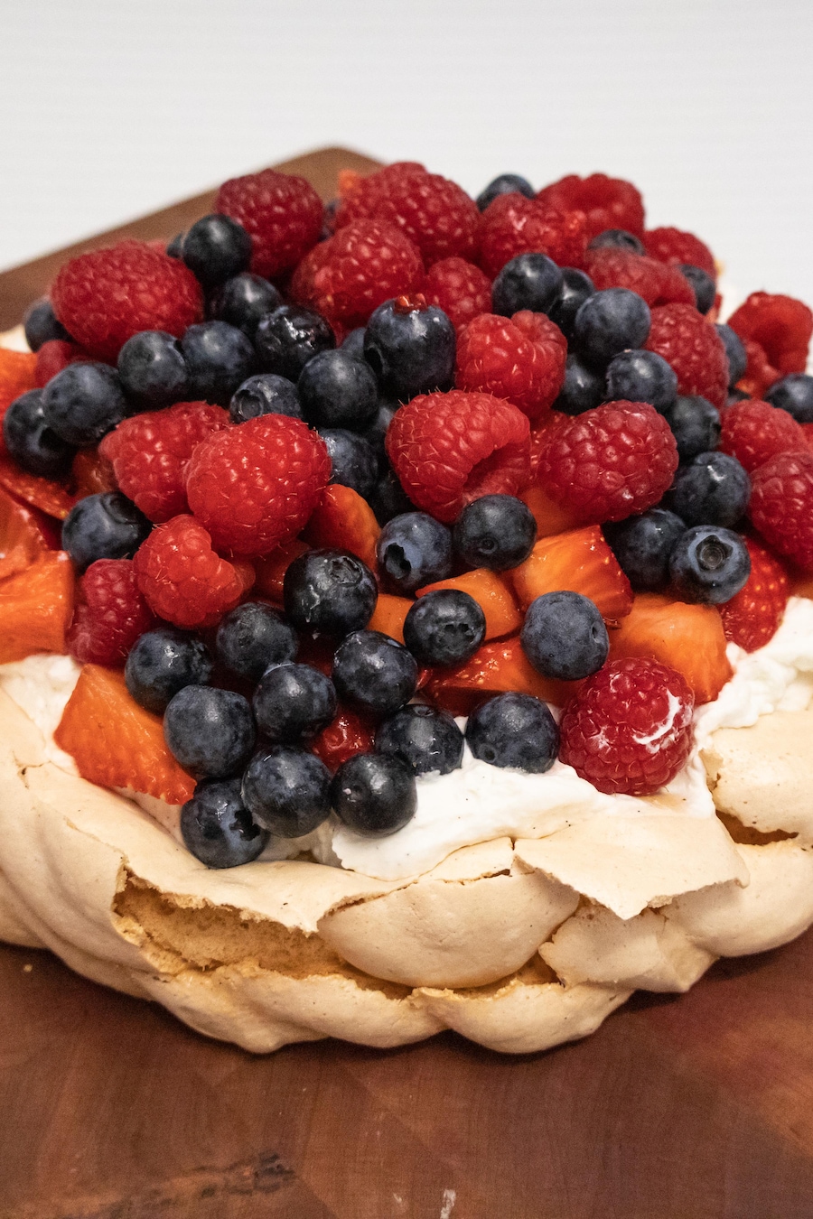 Un pavlova garni de crème fouettée, de fraises, framboises et bleuets.