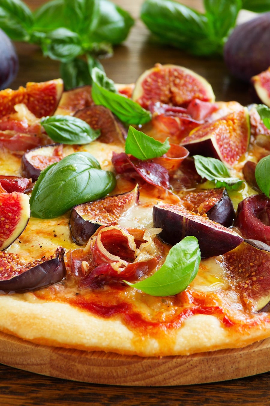 Une pizza recouverte de figues, de basilic, de fromage et de prosciutto.